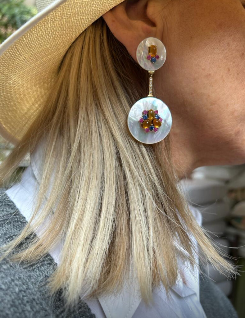 close-up shot of a woman wearing a the MOONLIGHT modular earrings by Aurvm Rome, featuring mother-of-pearl discs and a cluster of coloured precious stones.