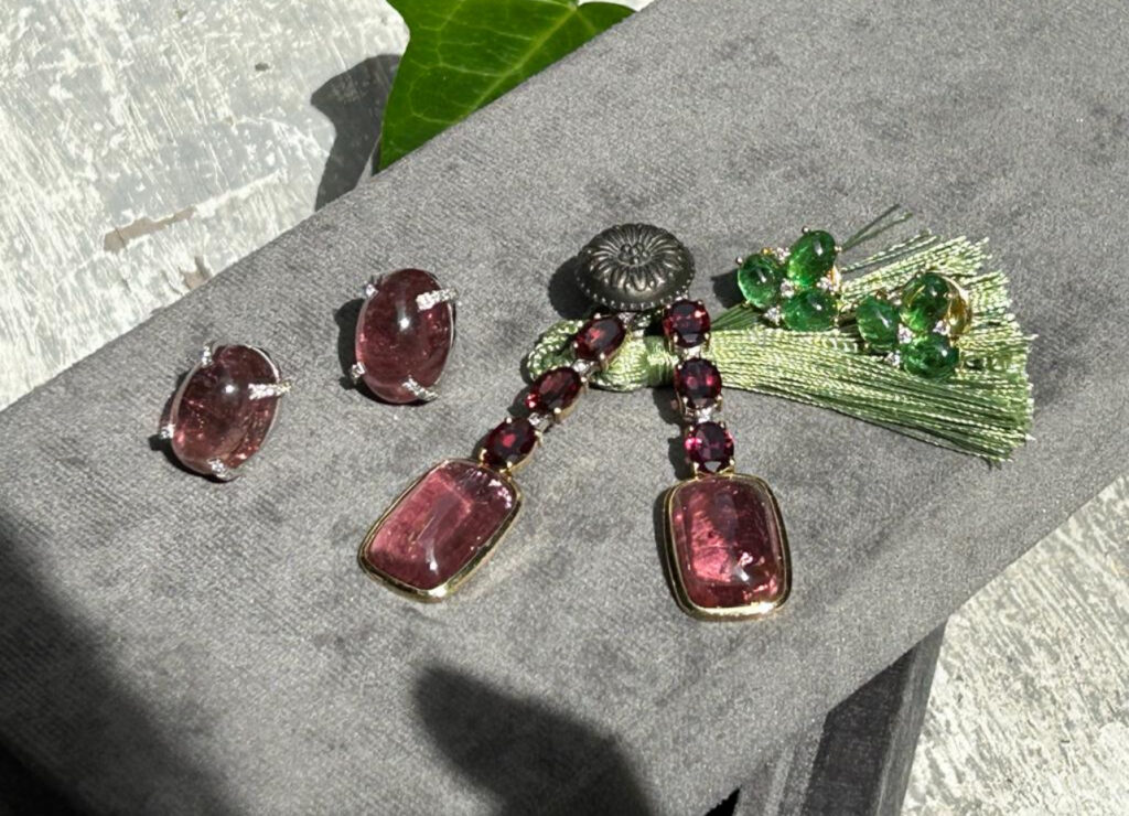 A selection of three SHERAZADE modular earrings by Aurvm Rome featuring pink and green tourmaline stones with diamonds on a grey velvet surface
